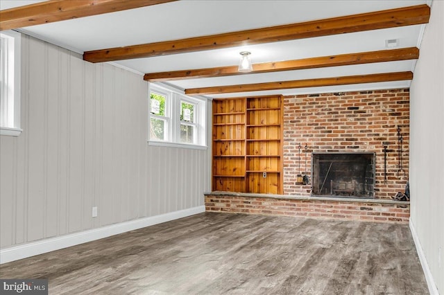 unfurnished living room featuring beamed ceiling, a brick fireplace, baseboards, wood finished floors, and built in features