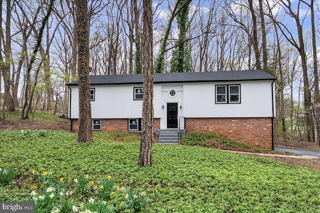 raised ranch featuring brick siding and a front lawn