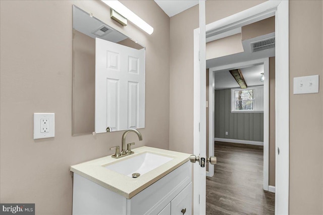 bathroom with wood finished floors, vanity, baseboards, and visible vents