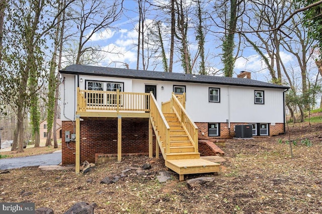 back of house with cooling unit, a wooden deck, stairs, and a chimney