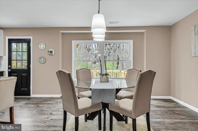 dining room with baseboards, visible vents, and wood finished floors