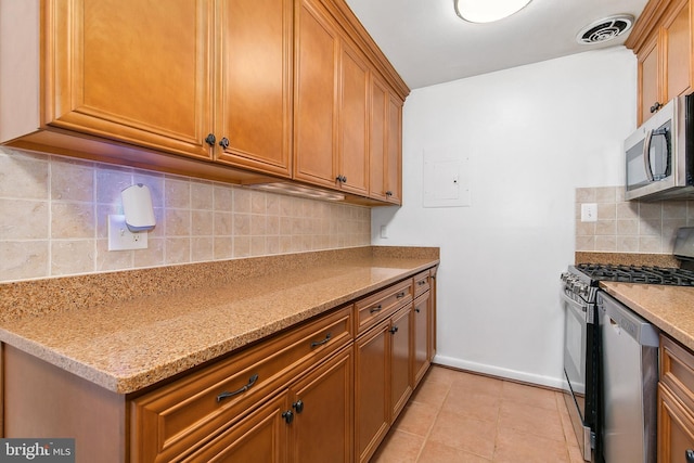 kitchen with light tile patterned floors, brown cabinets, decorative backsplash, visible vents, and stainless steel appliances
