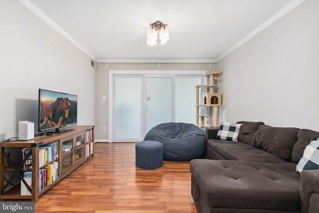 living room featuring crown molding, visible vents, wood finished floors, and baseboards