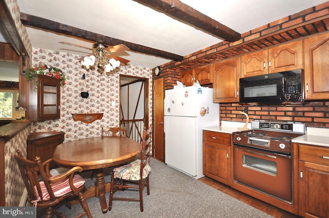 kitchen with freestanding refrigerator, black microwave, stove, wallpapered walls, and a ceiling fan