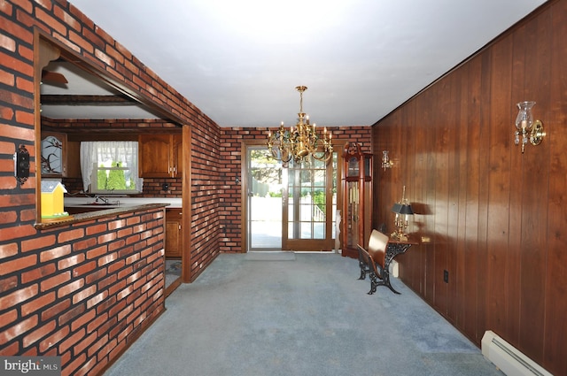 interior space with wooden walls, an inviting chandelier, brick wall, carpet, and a baseboard heating unit