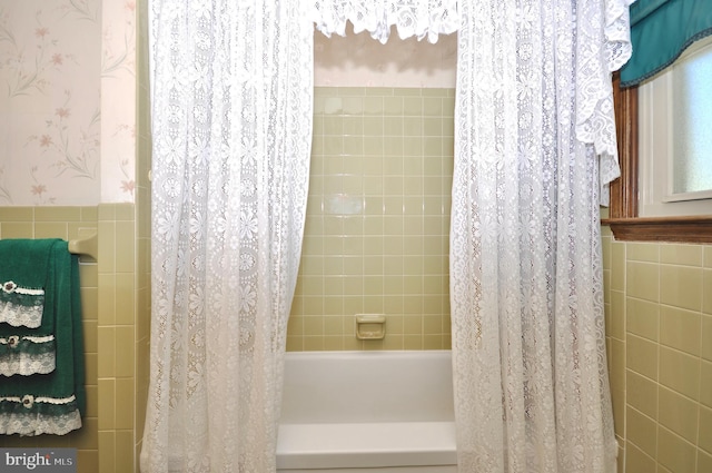 bathroom with shower / tub combo with curtain and tile walls