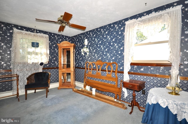 sitting room with carpet flooring, a ceiling fan, and wallpapered walls