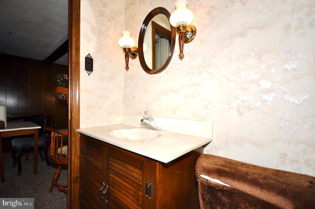 bathroom with vanity, wood walls, and wallpapered walls