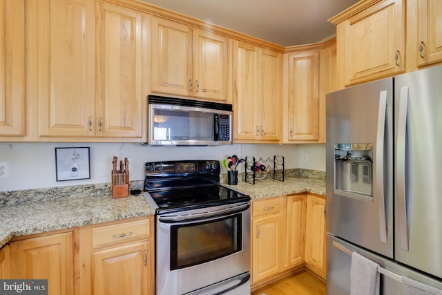 119 Bald Eagle Dr, Montross, VA 22520 - kitchen featuring stainless steel appliances, light stone countertops, light wood-style floors, and light brown cabinets