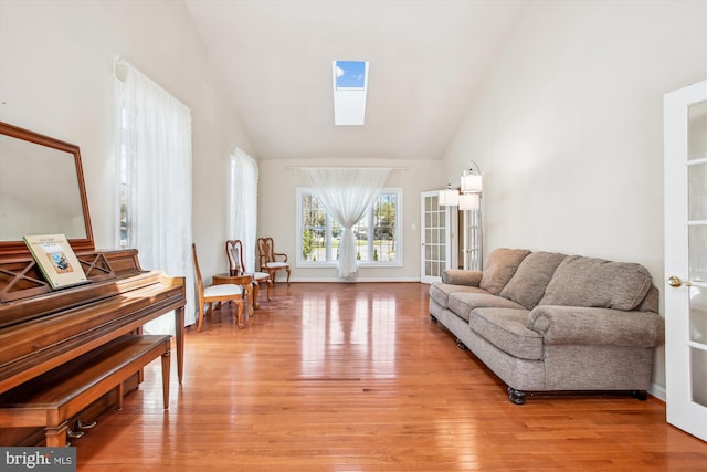 sitting room with vaulted ceiling with skylight and light wood-type flooring