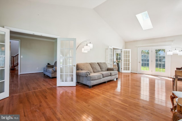 living room with french doors, a skylight, stairway, hardwood / wood-style floors, and high vaulted ceiling
