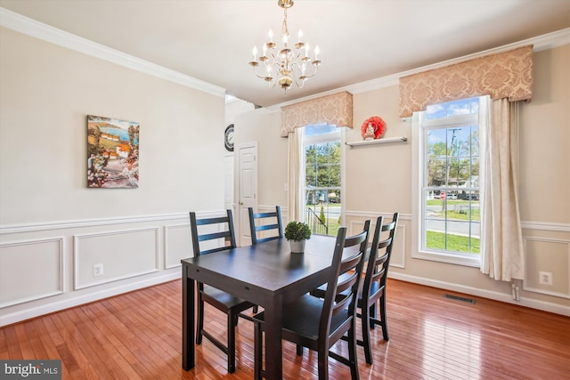 dining room featuring crown molding, visible vents, a chandelier, and wood-type flooring