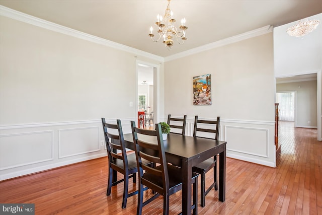 dining space with wainscoting, an inviting chandelier, crown molding, and light wood finished floors