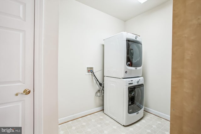 laundry room with baseboards, stacked washer / dryer, and laundry area
