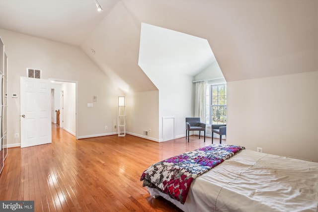 bedroom with light wood-type flooring, baseboards, visible vents, and lofted ceiling