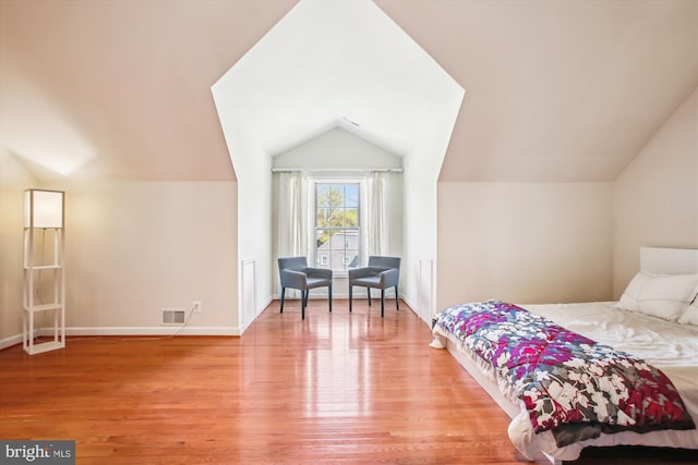 bedroom with vaulted ceiling, light wood-style floors, visible vents, and baseboards