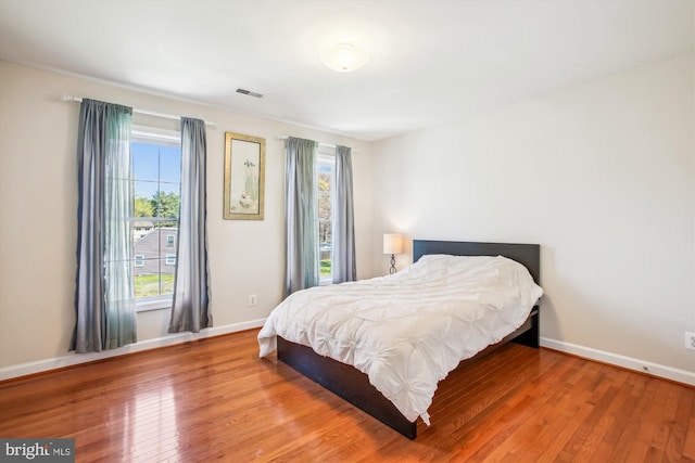 bedroom featuring hardwood / wood-style floors, visible vents, and multiple windows