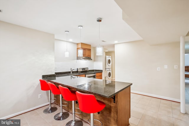 kitchen with a kitchen breakfast bar, tasteful backsplash, stacked washer / drying machine, electric range, and baseboards