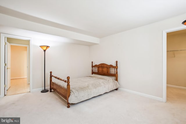 carpeted bedroom featuring a walk in closet, a closet, and baseboards