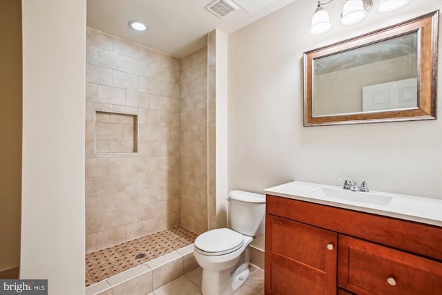 full bathroom with a tile shower, visible vents, toilet, and vanity