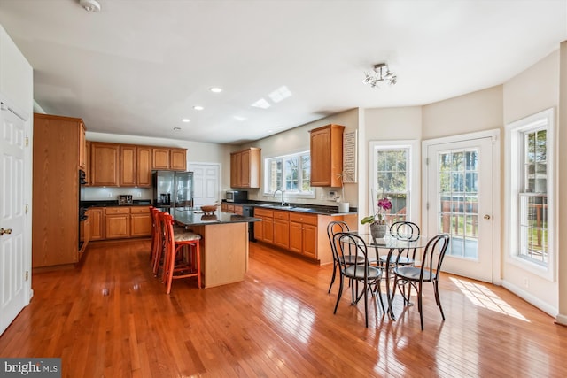 kitchen featuring dark countertops, light wood-style flooring, a kitchen island, and stainless steel refrigerator with ice dispenser