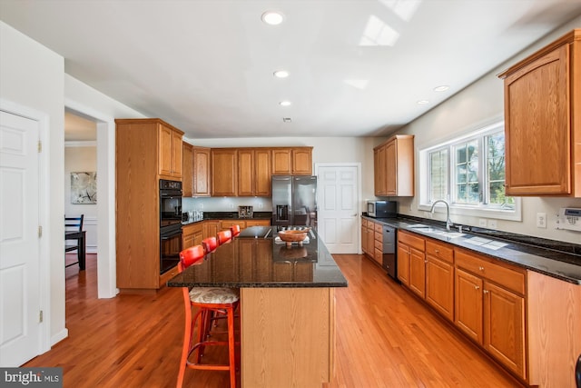 kitchen with a kitchen island, light wood finished floors, stainless steel appliances, and a sink