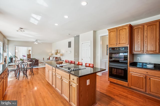 kitchen with recessed lighting, light wood-style floors, a kitchen island, and black appliances