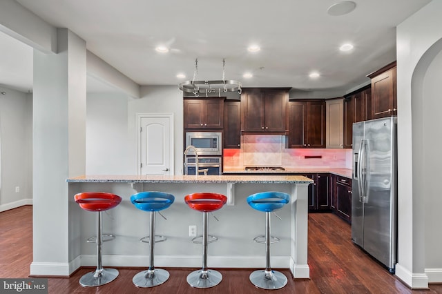 15343 Tewkesbury Pl, Upper Marlboro, MD 20774 - kitchen featuring appliances with stainless steel finishes, baseboards, dark brown cabinetry, a kitchen breakfast bar, and recessed lighting