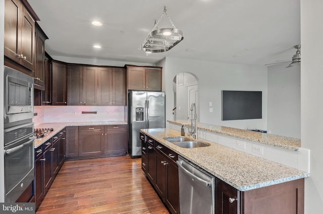 15343 Tewkesbury Pl, Upper Marlboro, MD 20774 - kitchen with stainless steel appliances, a sink, arched walkways, wood finished floors, and tasteful backsplash