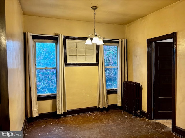 unfurnished dining area featuring baseboards, a chandelier, and radiator heating unit