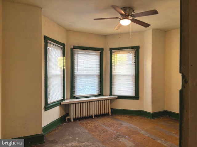 unfurnished room with baseboards, a ceiling fan, and radiator heating unit