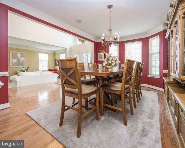 dining area with a notable chandelier, light wood-style flooring, baseboards, and ornamental molding