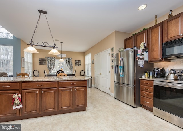 kitchen with hanging light fixtures, decorative backsplash, appliances with stainless steel finishes, and light stone counters
