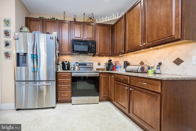 kitchen featuring appliances with stainless steel finishes, light tile patterned floors, light stone counters, and backsplash