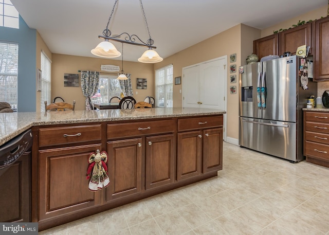 kitchen featuring light tile patterned floors, light stone counters, dishwasher, stainless steel fridge, and hanging light fixtures