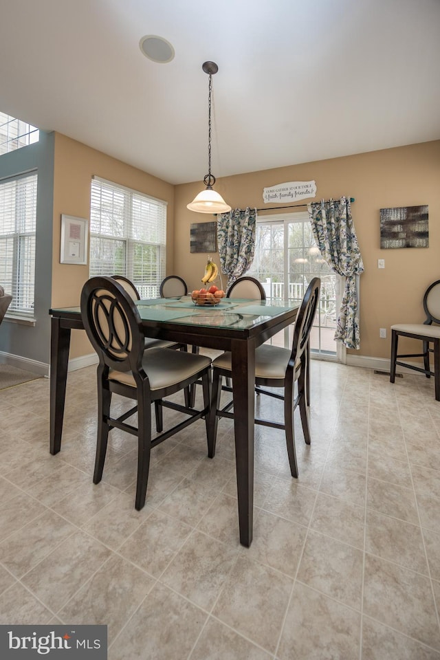 dining space with a healthy amount of sunlight, light tile patterned floors, and baseboards
