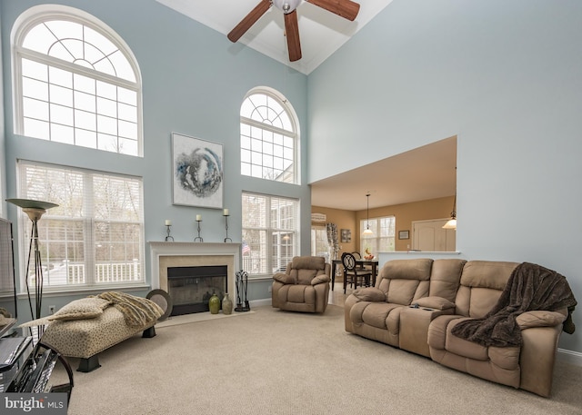 living room with ceiling fan, high vaulted ceiling, carpet flooring, and a premium fireplace