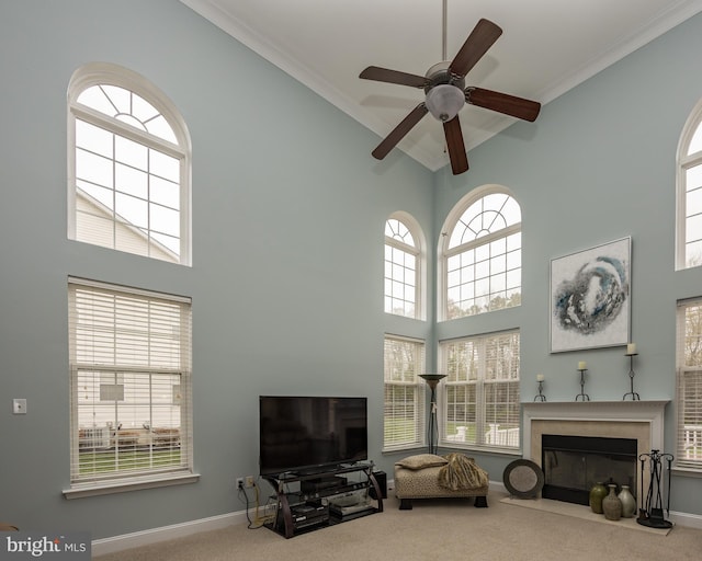 carpeted living area featuring high vaulted ceiling, baseboards, a ceiling fan, and a glass covered fireplace