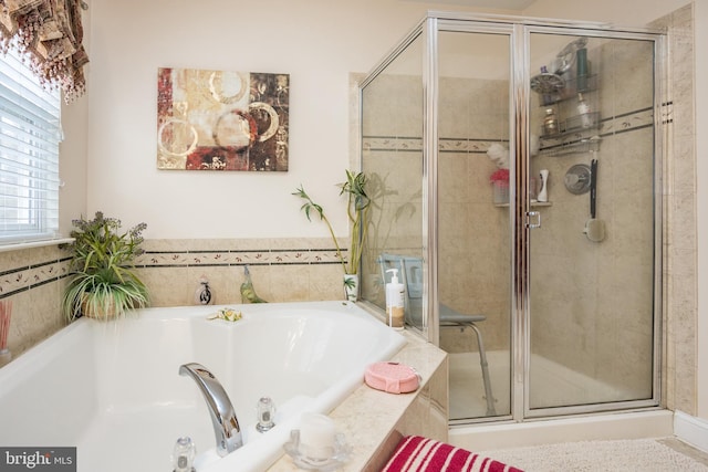 bathroom featuring a shower stall and a bath