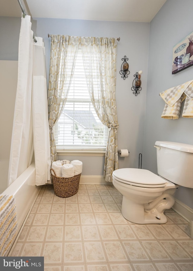 bathroom featuring shower / tub combo, baseboards, and toilet