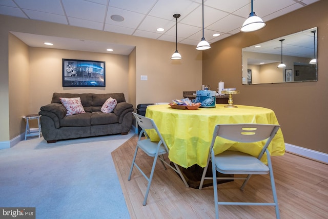 dining space featuring baseboards, a drop ceiling, and wood finished floors