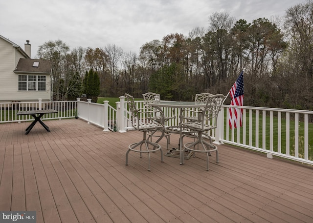 wooden deck featuring outdoor dining area and a lawn