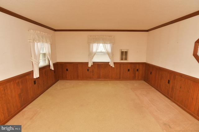 empty room featuring wooden walls, a wainscoted wall, light carpet, and a healthy amount of sunlight
