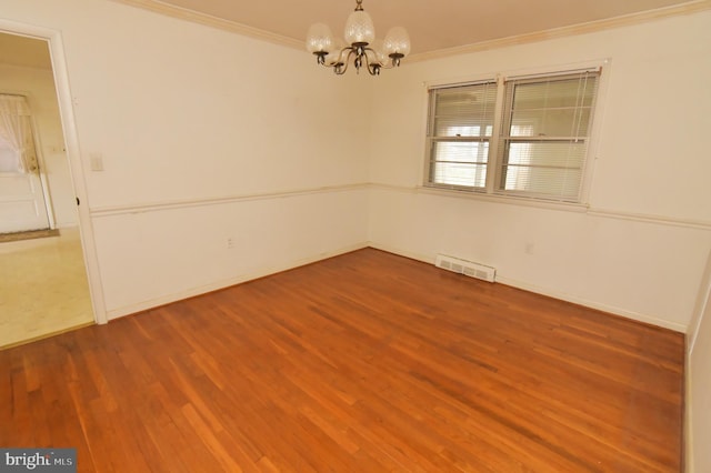 unfurnished room featuring baseboards, a chandelier, crown molding, visible vents, and wood finished floors
