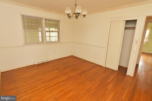 unfurnished dining area featuring a chandelier, crown molding, wood finished floors, and visible vents