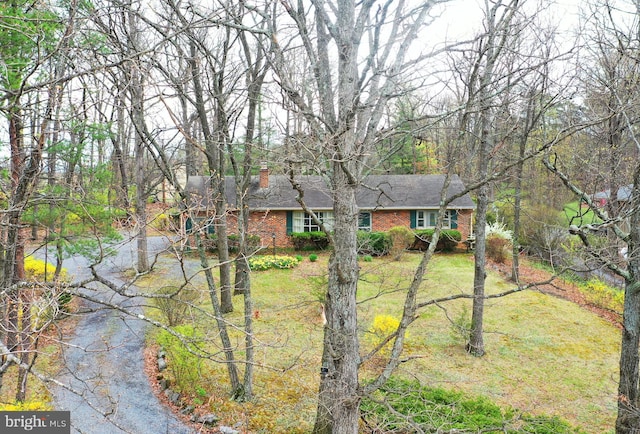 view of front of house featuring a front yard, brick siding, and a chimney