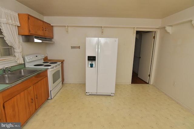 kitchen featuring brown cabinets, under cabinet range hood, white appliances, and light floors