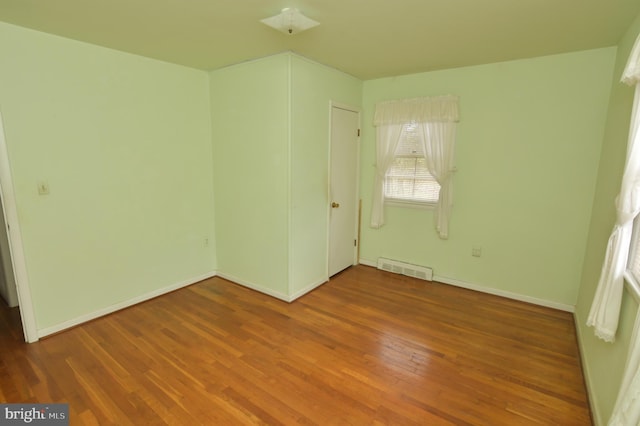 unfurnished bedroom featuring wood finished floors, baseboards, and visible vents
