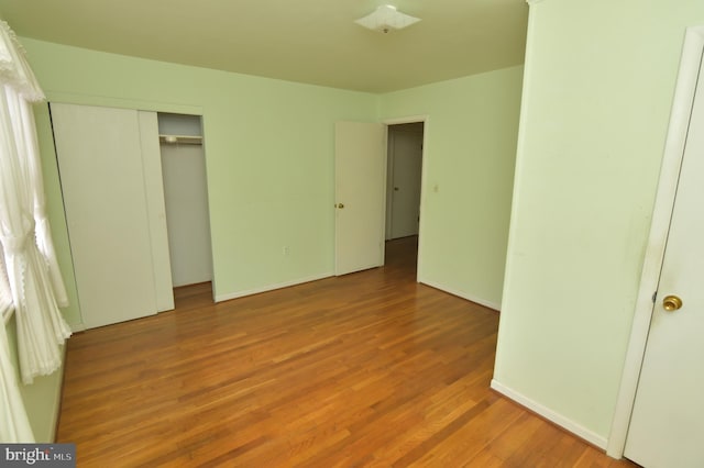 unfurnished bedroom featuring a closet, baseboards, and wood finished floors