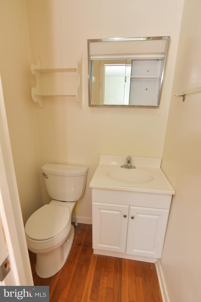 bathroom featuring toilet, vanity, wood finished floors, and baseboards